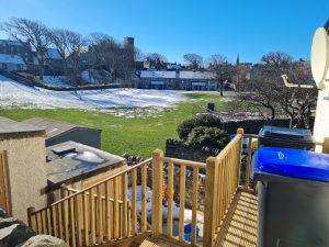 Looking over the bin balcony, steps and sheds across the Wally Green under the melting snow